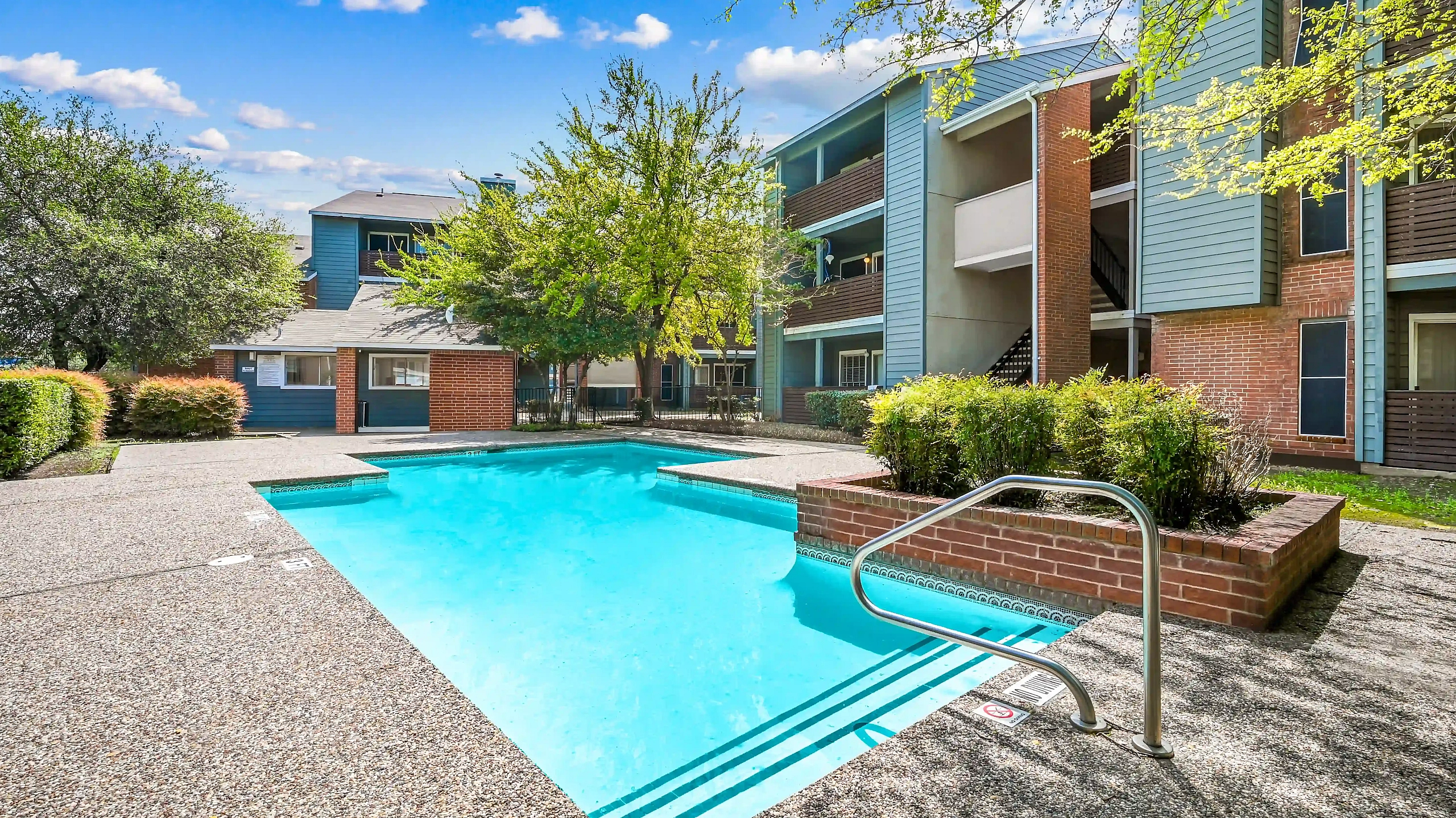 Inviting outdoor swimming pool area surrounded by modern apartment buildings and lush greenery, perfect for relaxation and leisure.