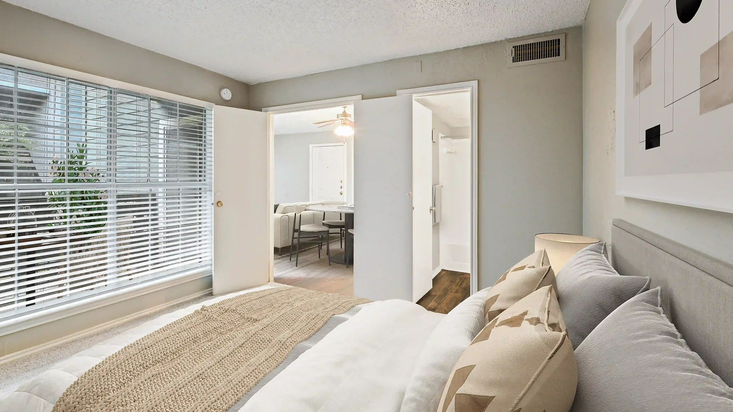 Bright bedroom with large windows and stylish decor, leading to an inviting open dining area.