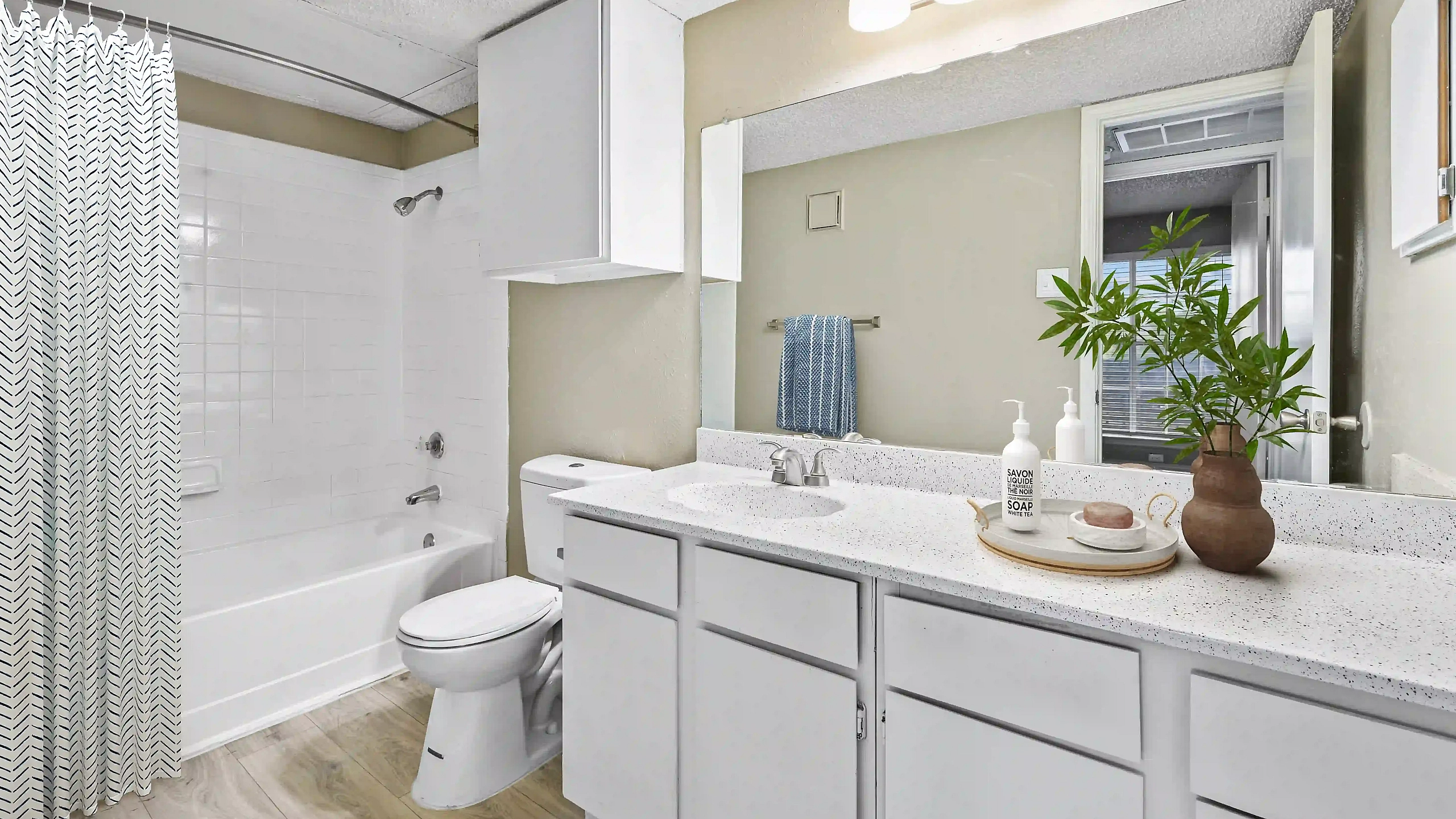 Bright and welcoming bathroom with stylish lighting, modern fixtures, and lush greenery accents.