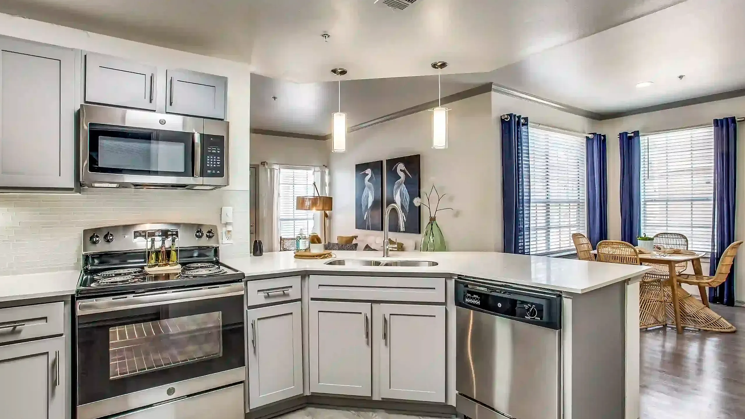 Contemporary kitchen with sleek stainless steel appliances, cozy breakfast nook, and bright open windows.