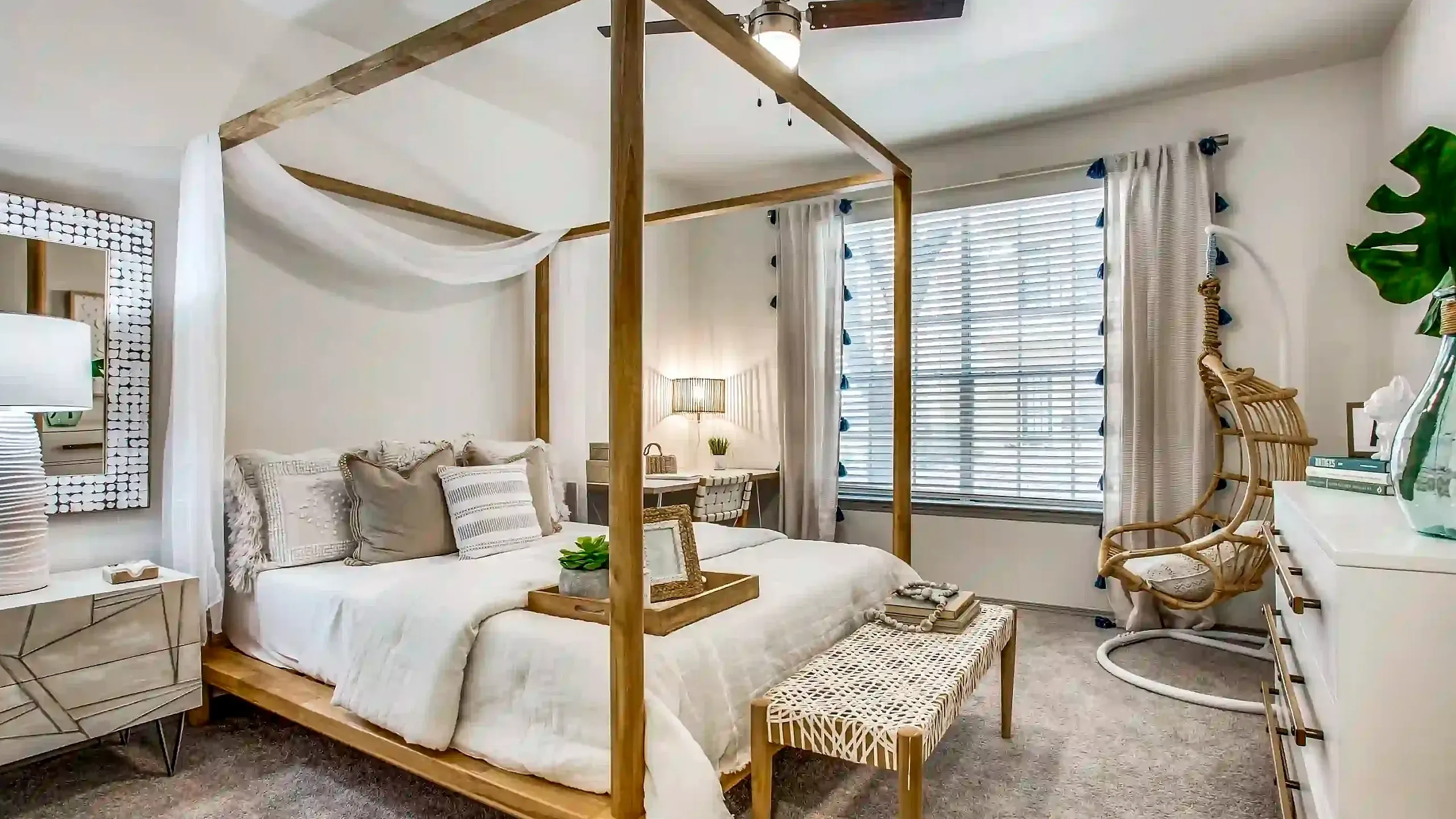 Elegant bedroom with a chic four-poster bed, stylish wicker chair, and modern decor, bathed in natural light.