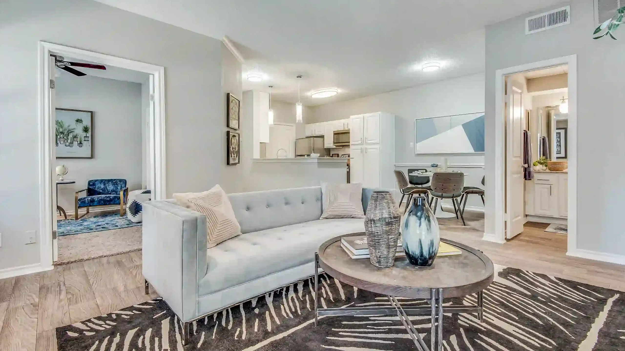 Elegant living room with plush sofa, wooden floors, and a modern open kitchen view, offering a warm and inviting atmosphere.