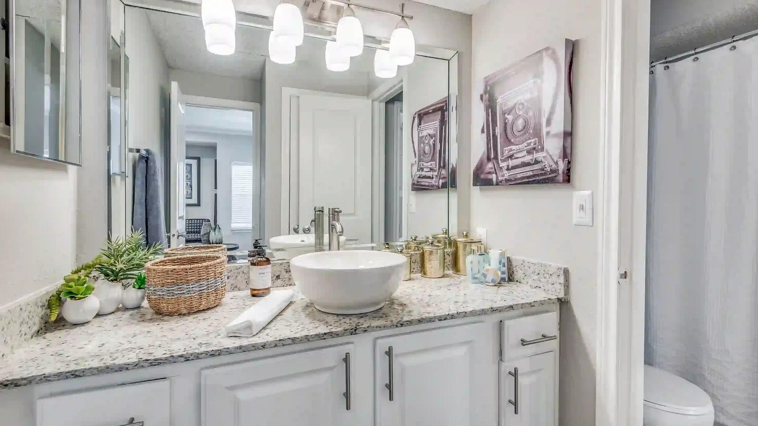 Elegant bathroom with modern fixtures, chic countertop decor, and a stylish vessel sink, offering a serene retreat.