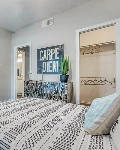 Inviting bedroom with contemporary decor features a cozy bed, abstract artwork, and walk-in closet.