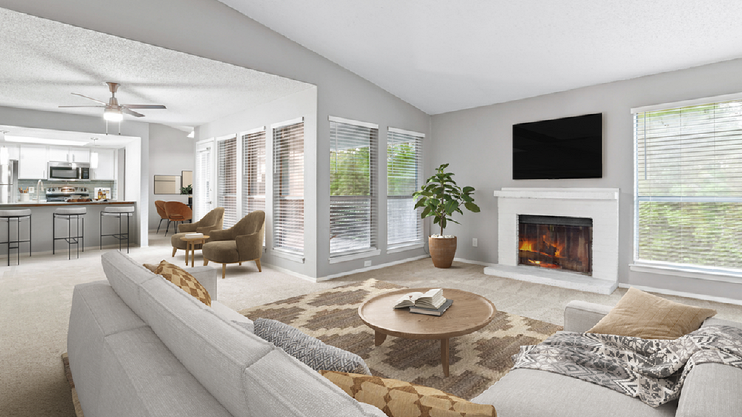 Bright and inviting living room with cozy fireplace, plush sofas, and elegant decor leading to a modern open kitchen.