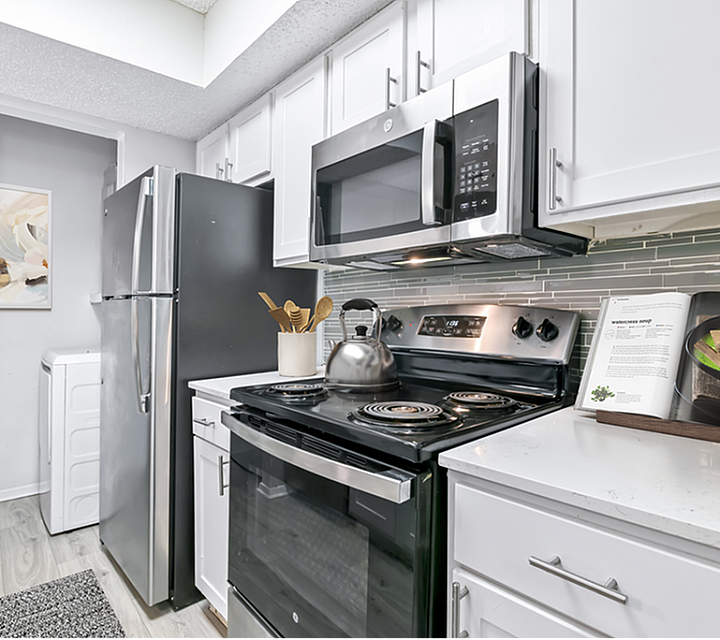 Modern kitchen with sleek stainless steel appliances, elegant backsplash, and cozy decor.