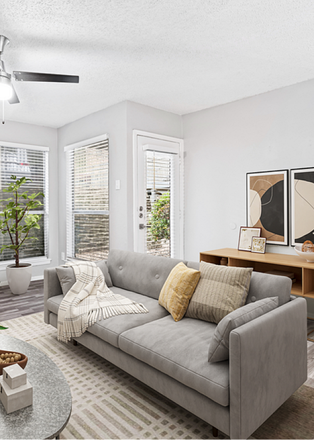Modern living room with elegant decor, cozy gray sofa, and large windows offering abundant natural light.