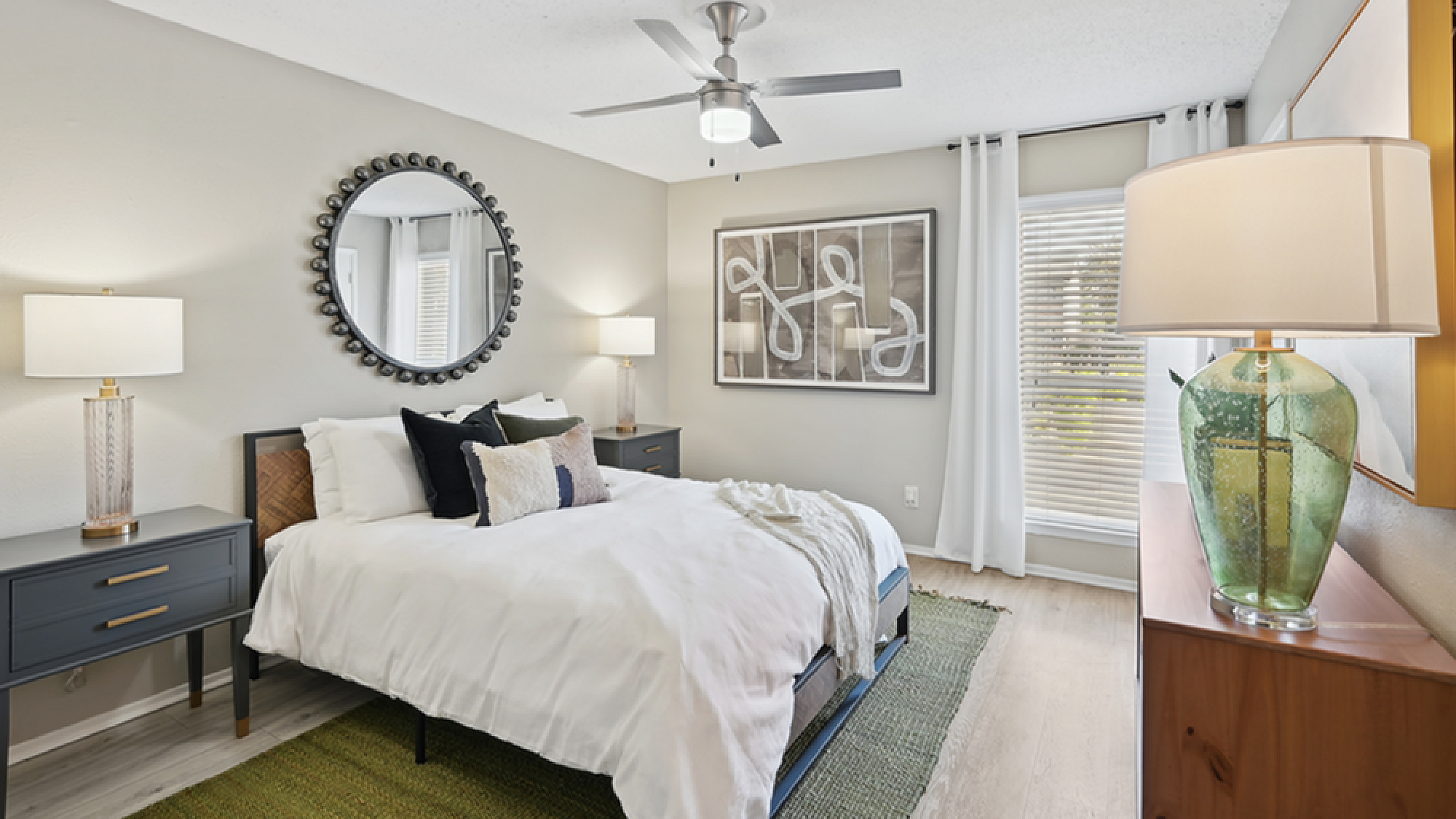 Chic and inviting bedroom with modern decor, featuring a plush bed, statement mirror, and abundant natural light.