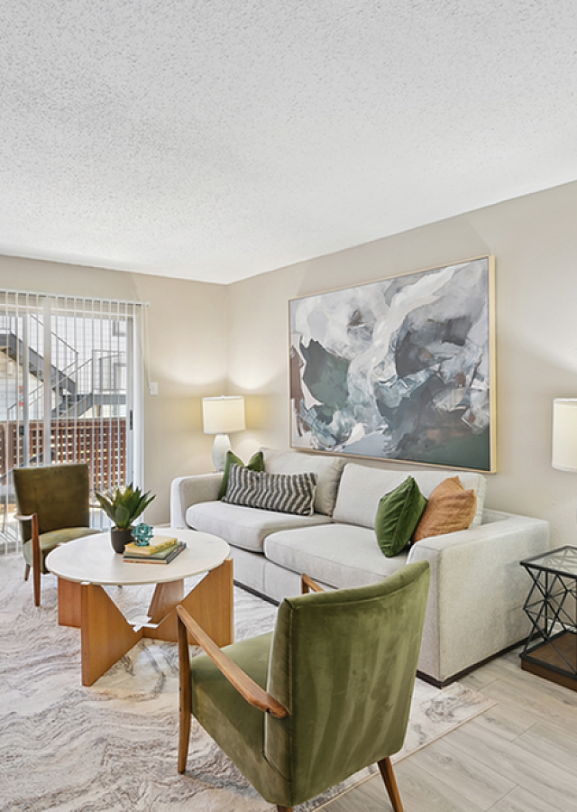 Inviting living room with elegant decor, featuring a modern sofa, stylish chairs, and vibrant plants, bathed in natural light from large windows.