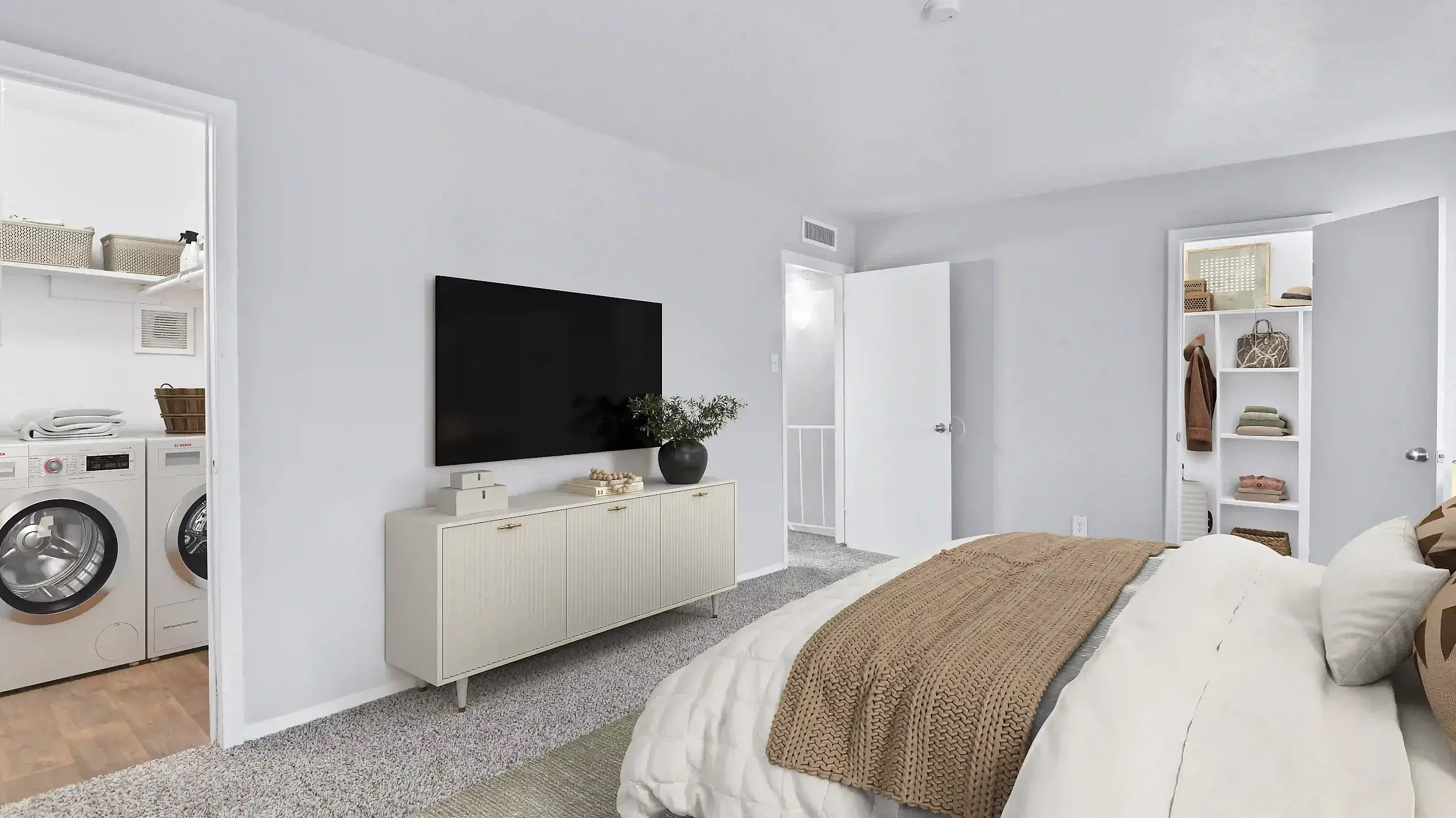 Bright bedroom with a wall-mounted TV, adjacent laundry area, and open closet.