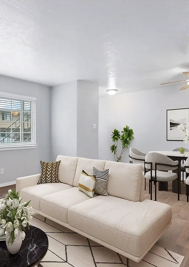 Chic open-concept living and dining area with elegant decor, plush seating, and abundant natural light through a large window.
