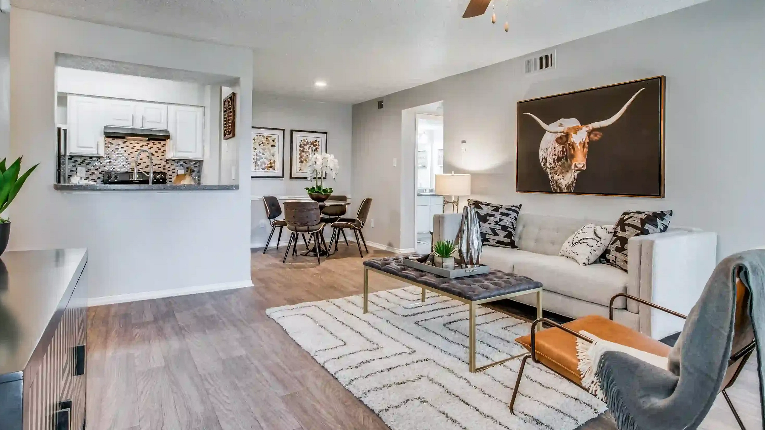 Modern living room featuring elegant decor, a cozy sofa, stylish artwork, and an open-concept kitchen with chic dining area.