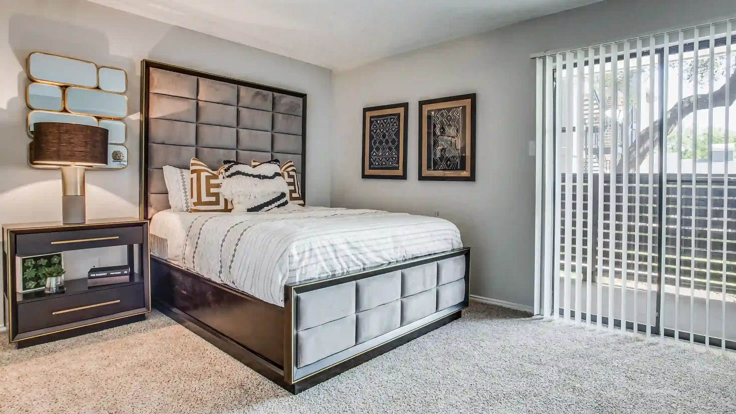 Bright bedroom with modern decor, plush bed, and natural light from sliding glass doors leading to a serene outdoor view.
