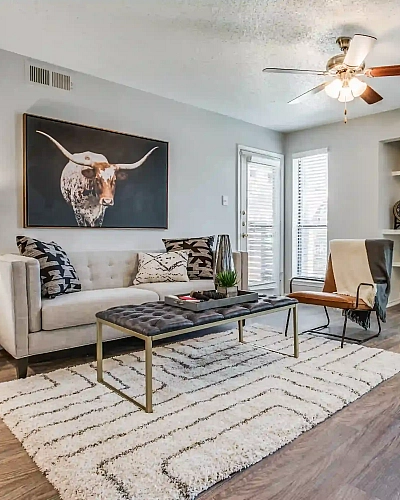 Modern living room with stylish decor, featuring a plush sofa, chic artwork, and large windows that flood the space with natural light.