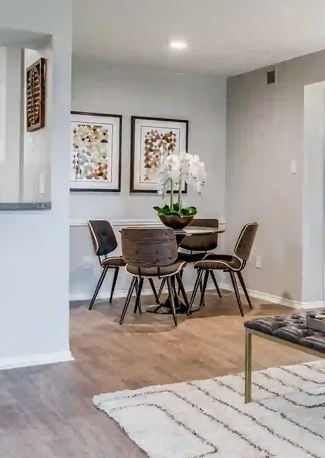 Modern living room with elegant decor, featuring a stylish open kitchen, cozy seating, and chic artwork.
