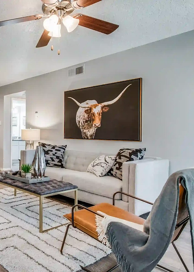 Elegant living space with cozy seating, stylish decor, and a modern kitchen in the background, featuring tasteful artwork and warm lighting.