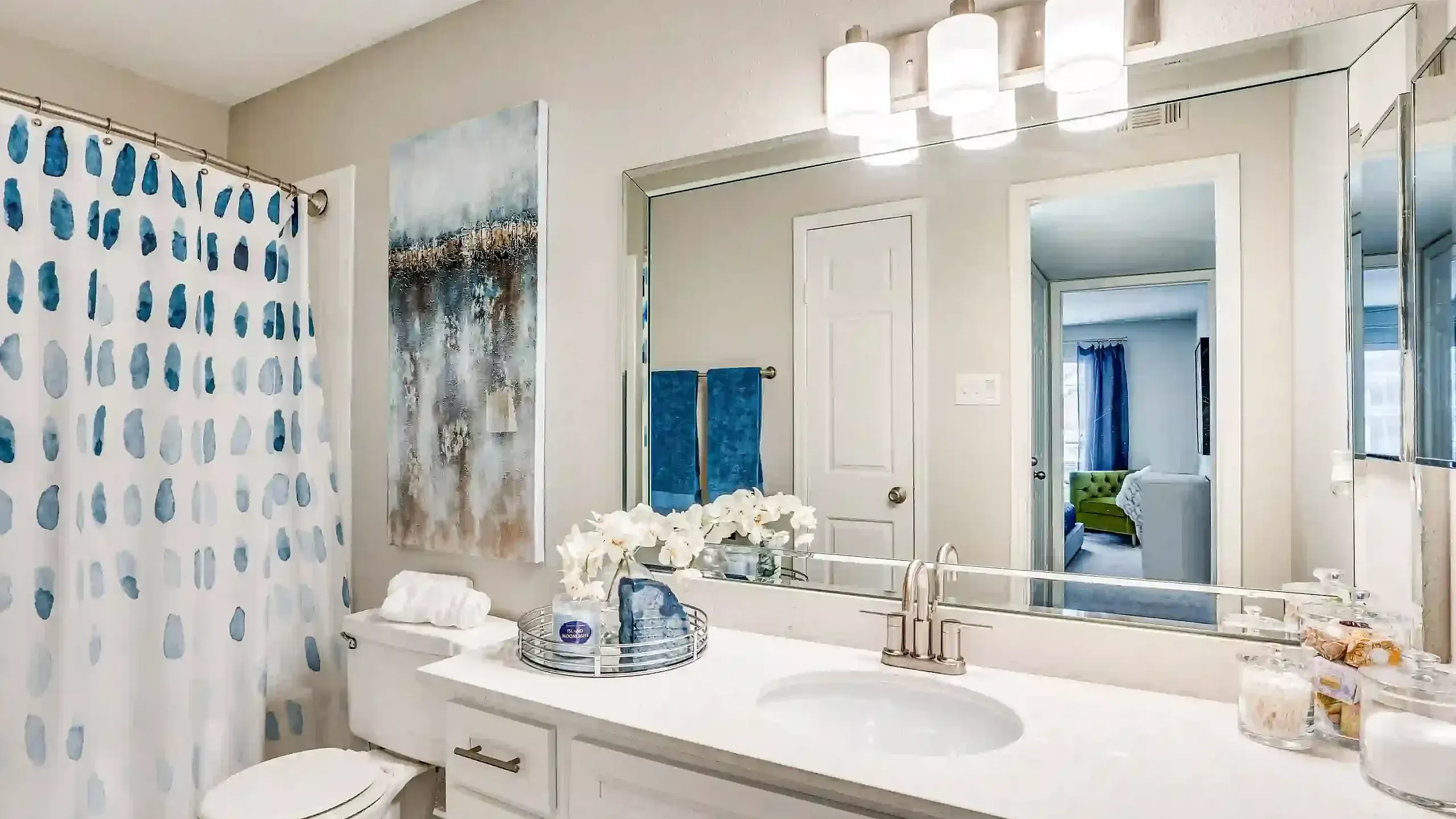 Modern bathroom with elegant decor, featuring a sleek vanity, large mirror, and artistic shower curtain, exuding an inviting and sophisticated ambiance.