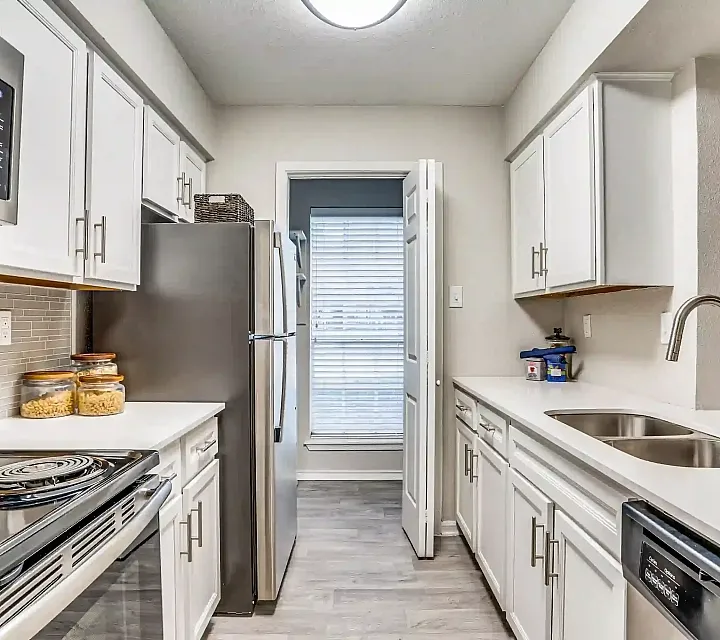 Modern kitchen with sleek stainless steel appliances, pristine white cabinetry, and stylish countertops, basking in natural light.