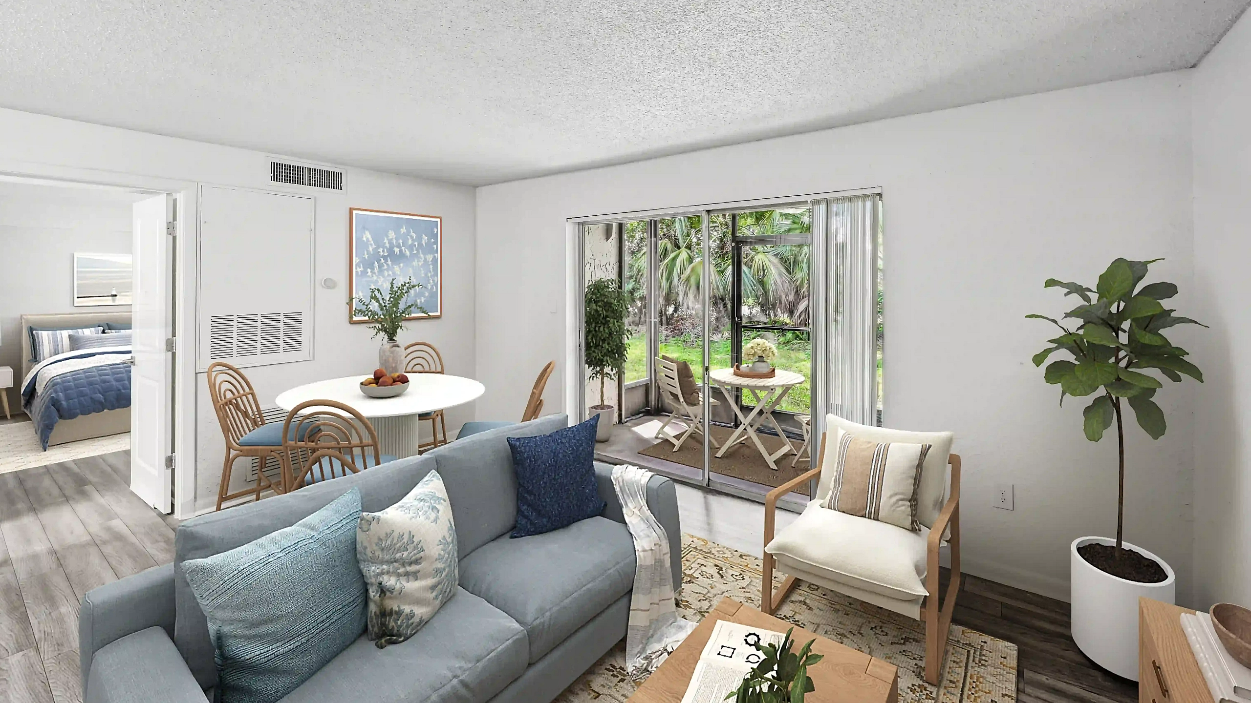 Bright apartment living room featuring a blue sofa, cozy seating, dining area, and sliding glass doors leading to a screened-in patio.