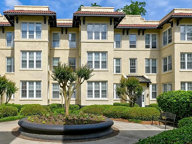 Charming apartment building with elegant architecture, surrounded by lush greenery and a serene courtyard.