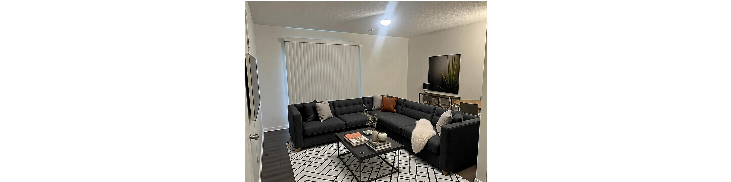Elegant living room showcasing a modern L-shaped sofa with plush cushions, stylish coffee table, and sleek dining area in an open-concept space.