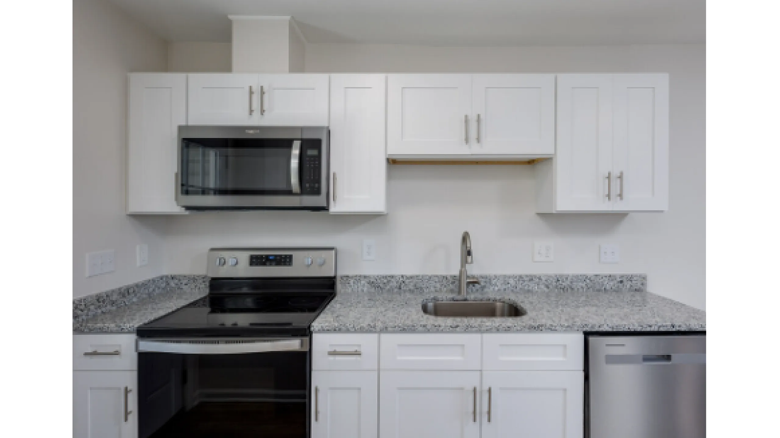 Modern kitchen with sleek white cabinets, granite countertops, and stainless steel appliances.