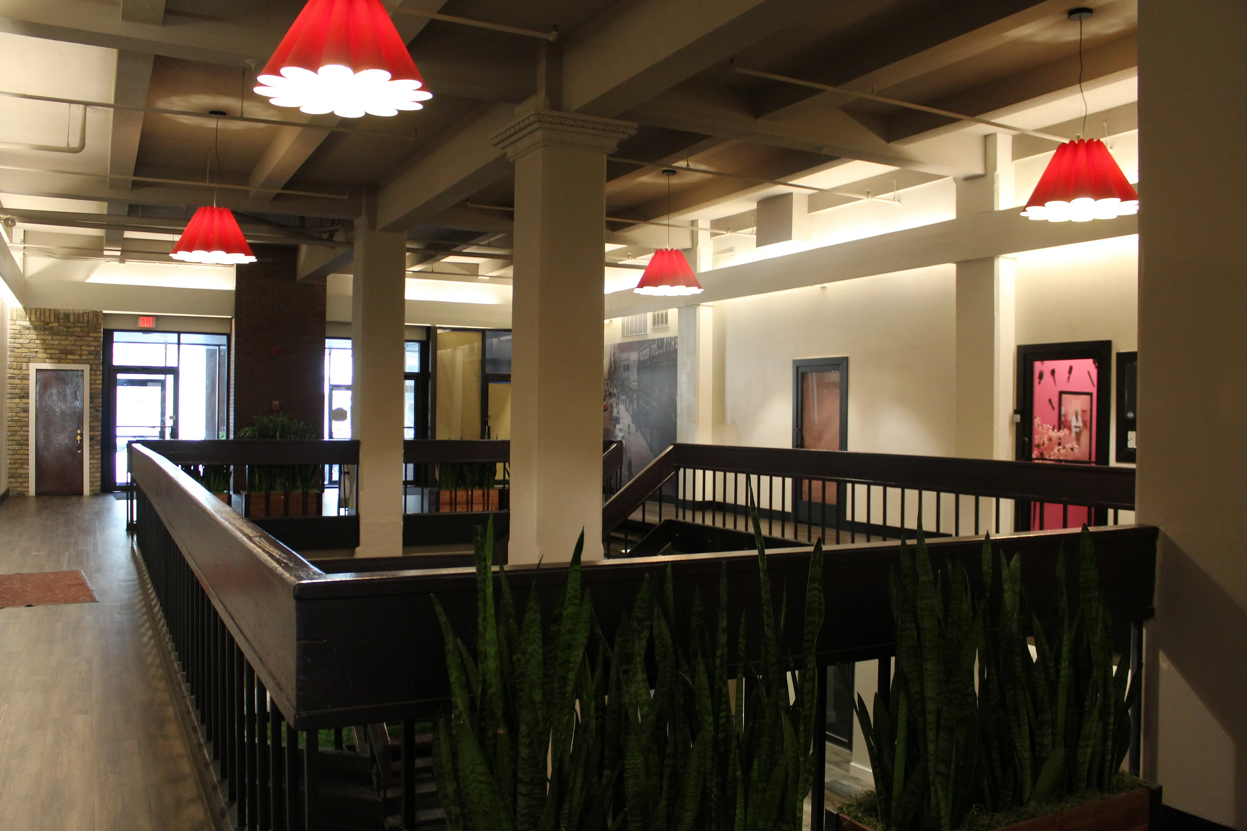 Elegant apartment lobby with modern lighting, sleek wood flooring, and inviting greenery.