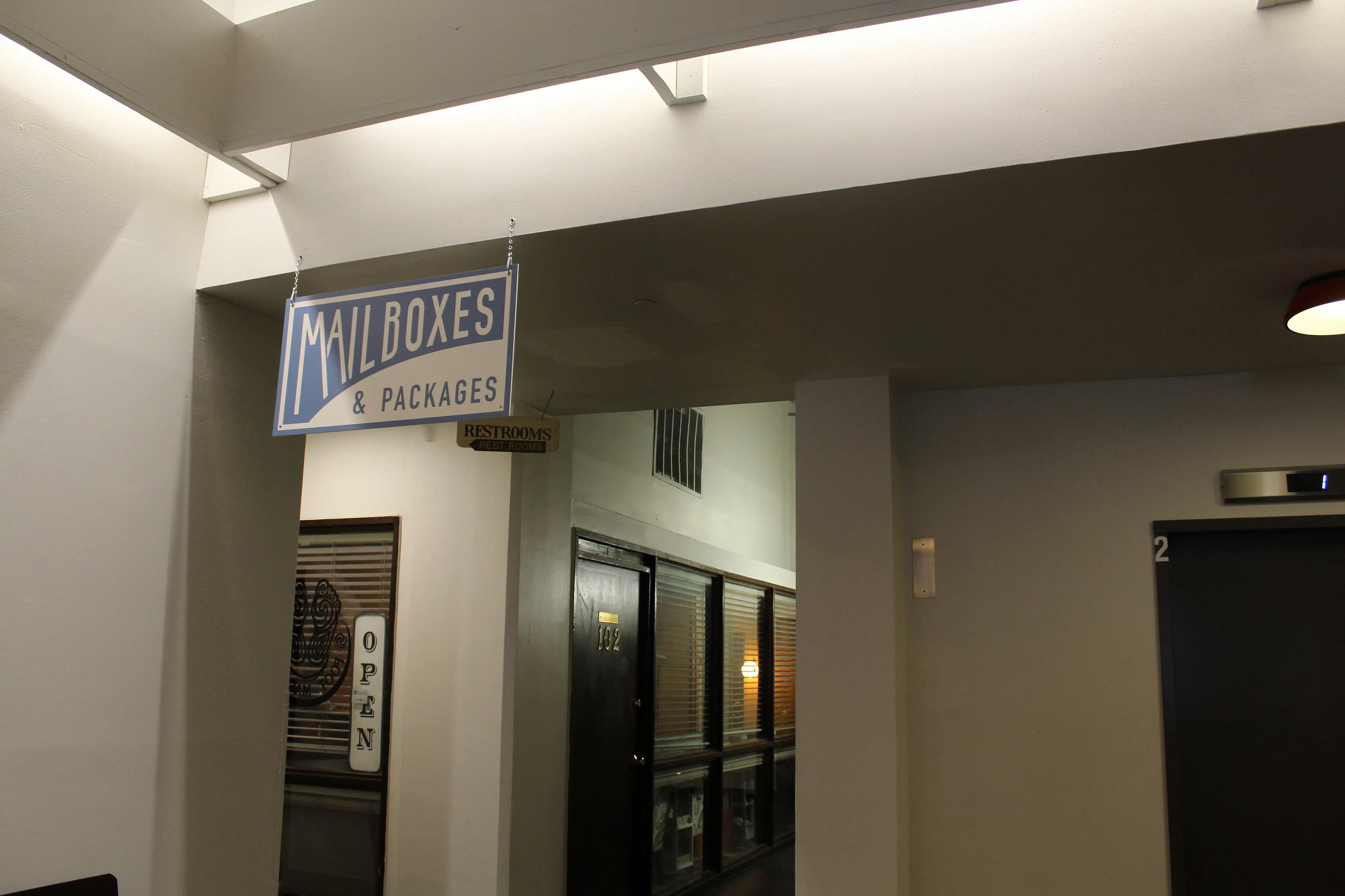 Inviting hallway with mailboxes and package service, featuring modern lighting and accessible elevator.
