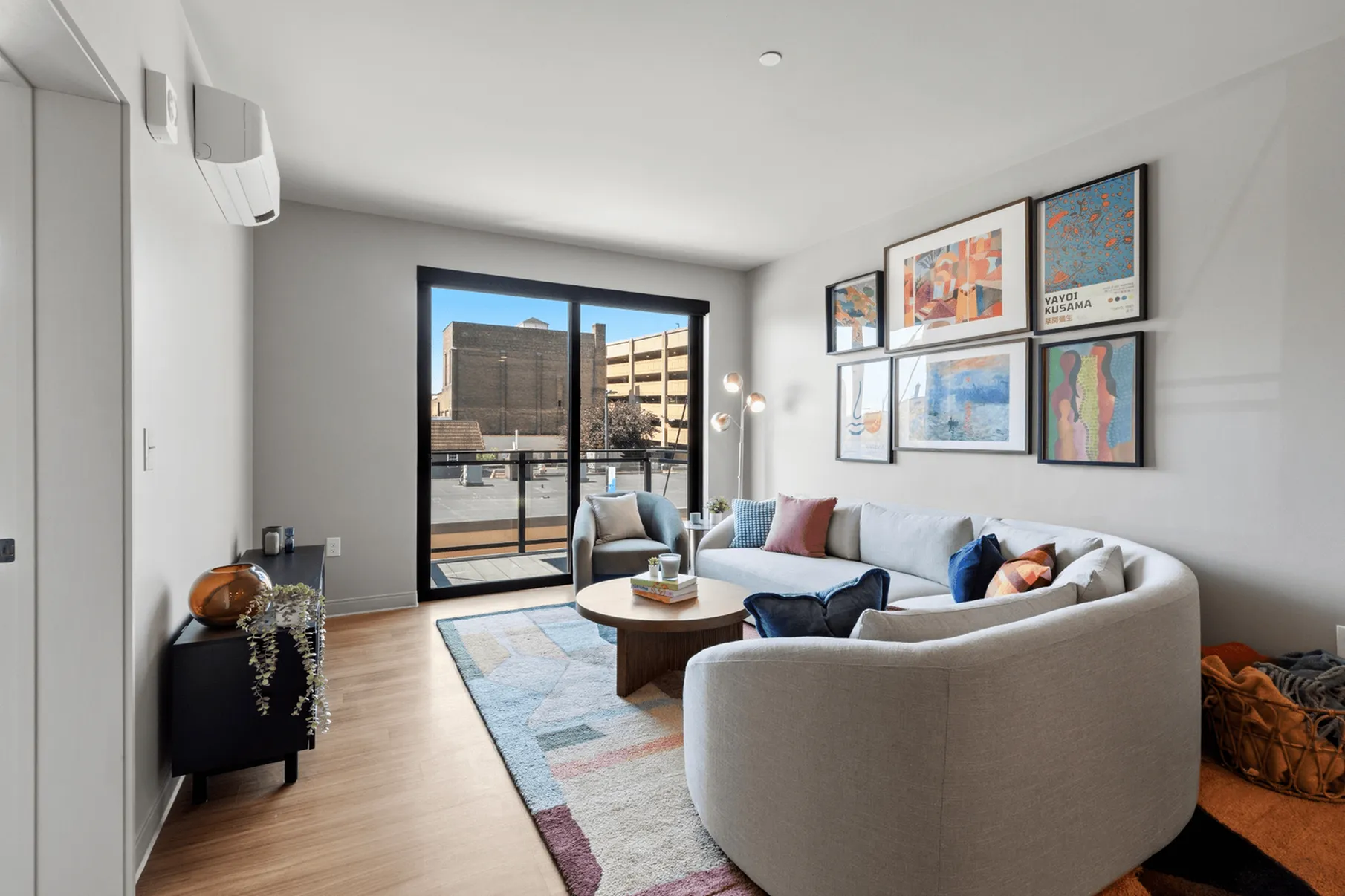 Inviting modern living room with stylish decor, featuring a cozy sectional sofa, vibrant artwork, and a sunlit balcony view.