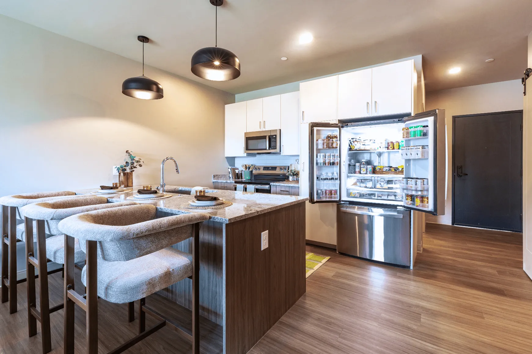 Modern kitchen with sleek appliances, elegant pendant lighting, and a spacious kitchen island with seating.