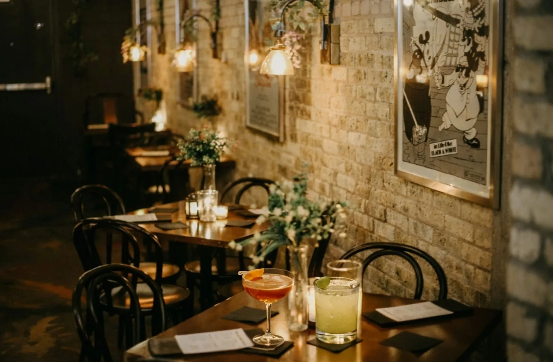Cozy restaurant with warm lighting, elegant wooden tables, and stylish cocktails, creating an inviting and intimate dining atmosphere.