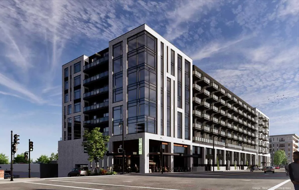 Modern urban apartment building with sleek glass façade and multiple balconies, set against a vibrant cityscape and blue sky.