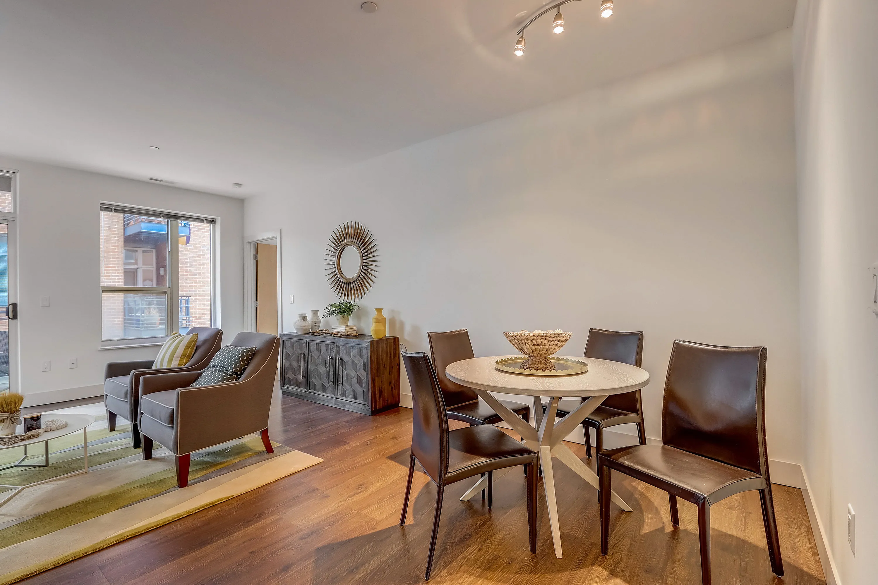 Elegant open-concept dining and living area with stylish decor, modern lighting, and rich wooden flooring.