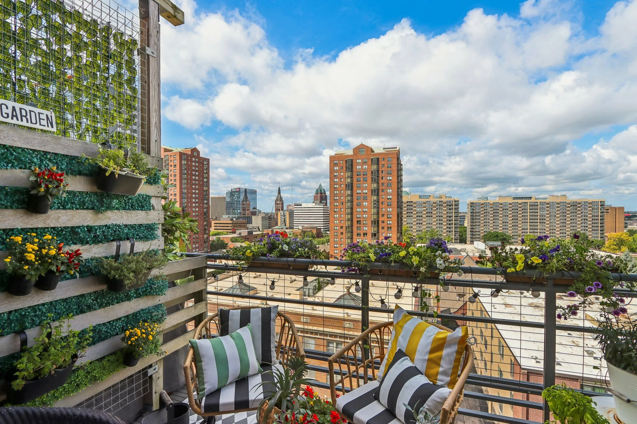 Charming city-view balcony adorned with vibrant flowers and cozy seating, perfect for relaxation.