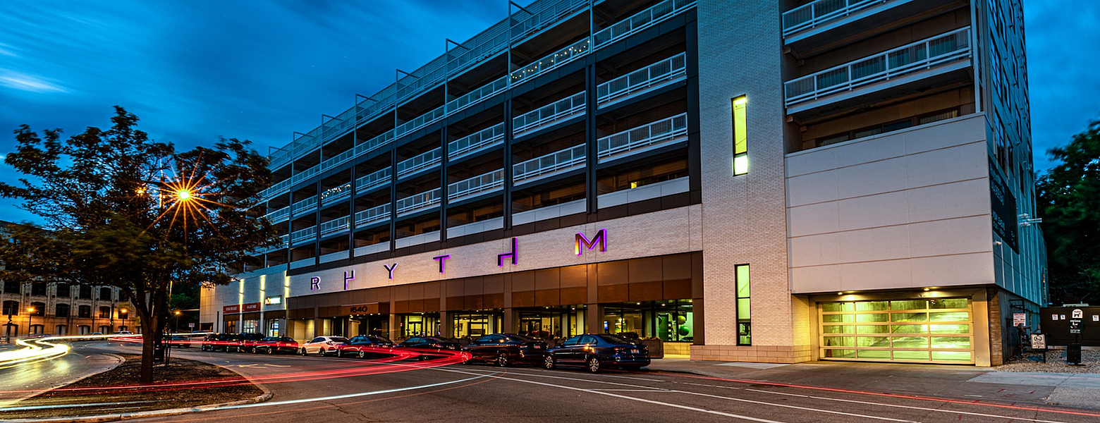 Modern multi-story building with sleek architecture and vibrant exterior lighting at dusk, showcasing stylish urban living.