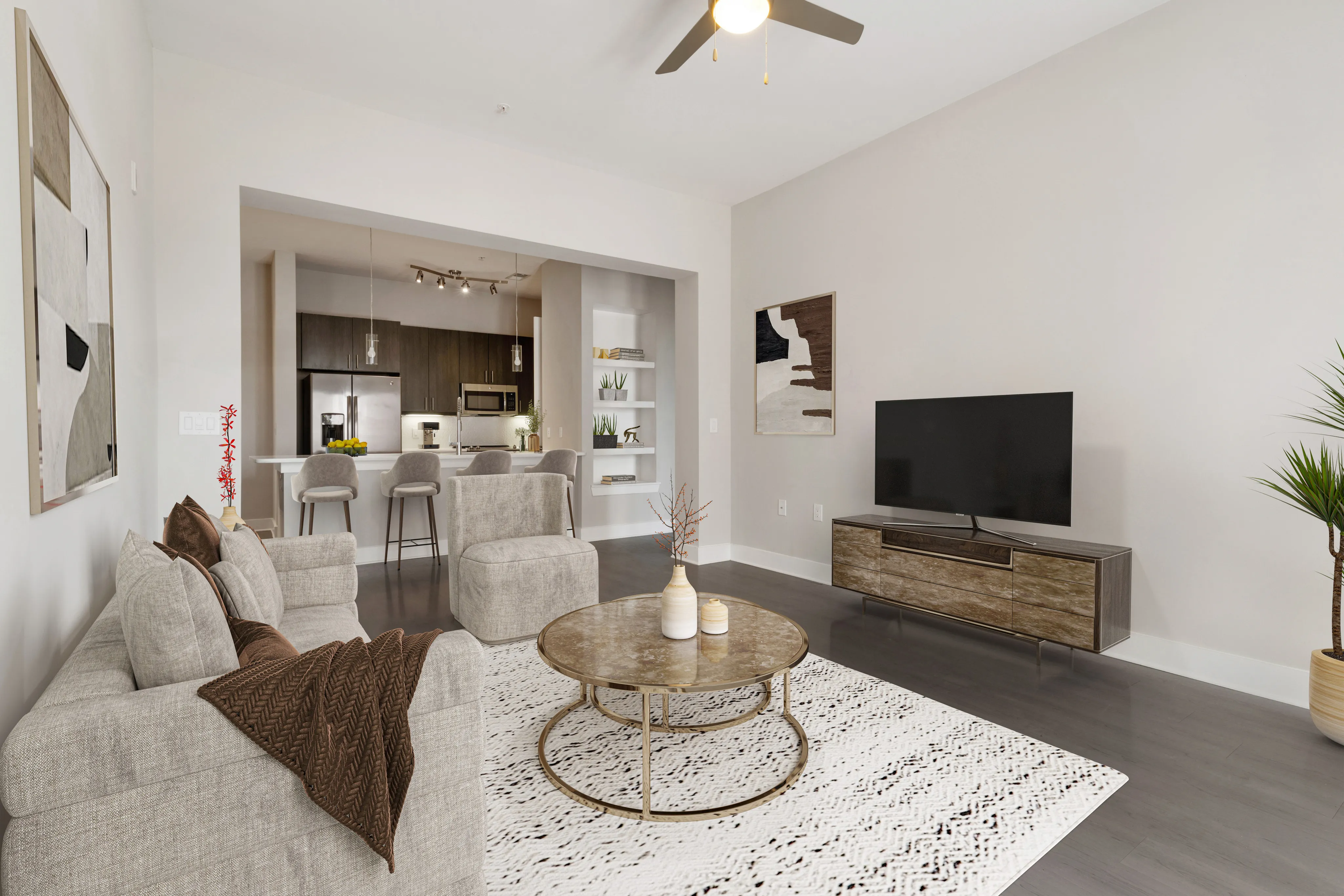 Modern open-concept living room with plush seating, elegant coffee table, and a stylish kitchen with breakfast bar in background. Bright, inviting space with sophisticated decor.