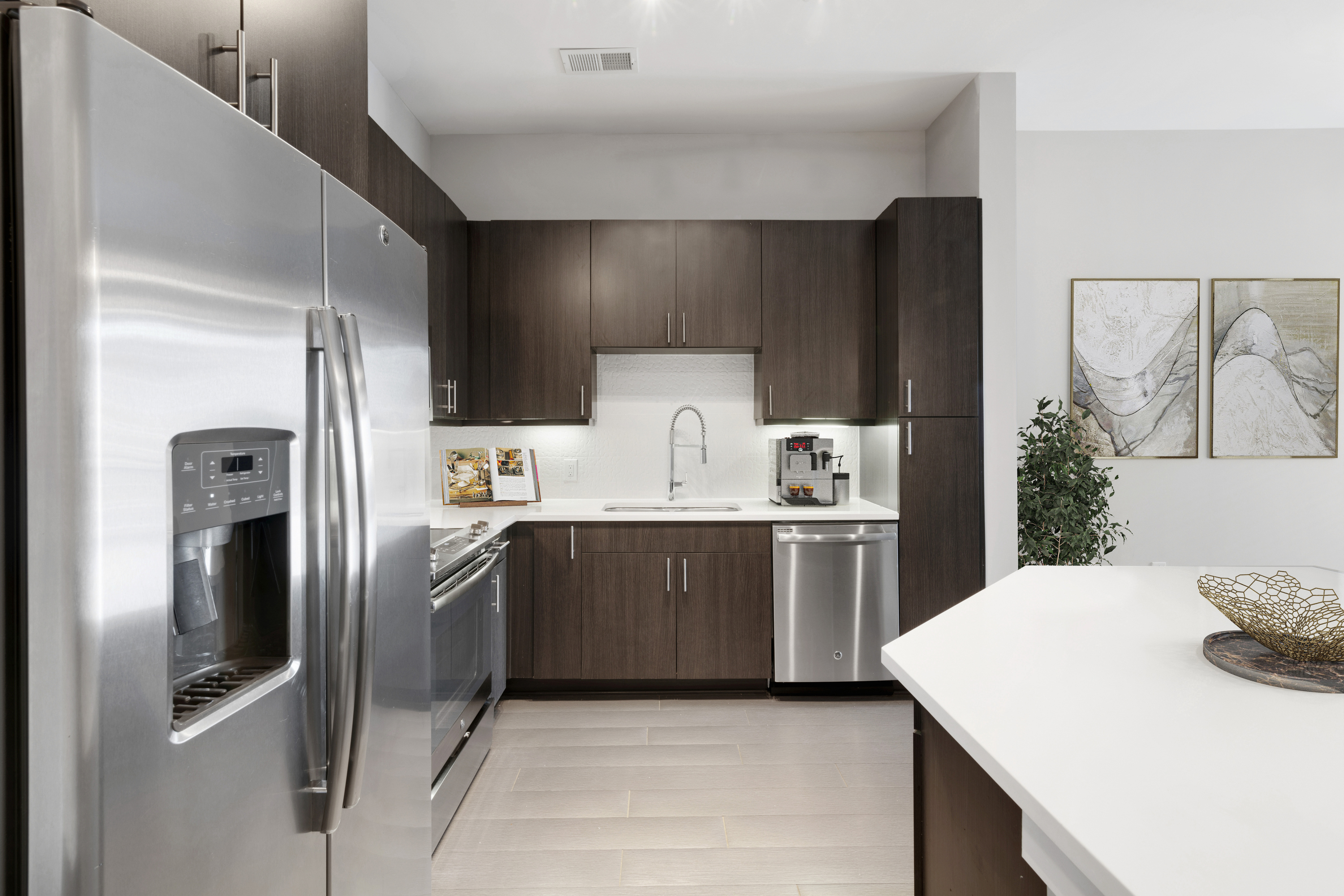 Modern kitchen design featuring stainless steel appliances, dark wood cabinets, and elegant artwork, creating a sophisticated cooking space.
