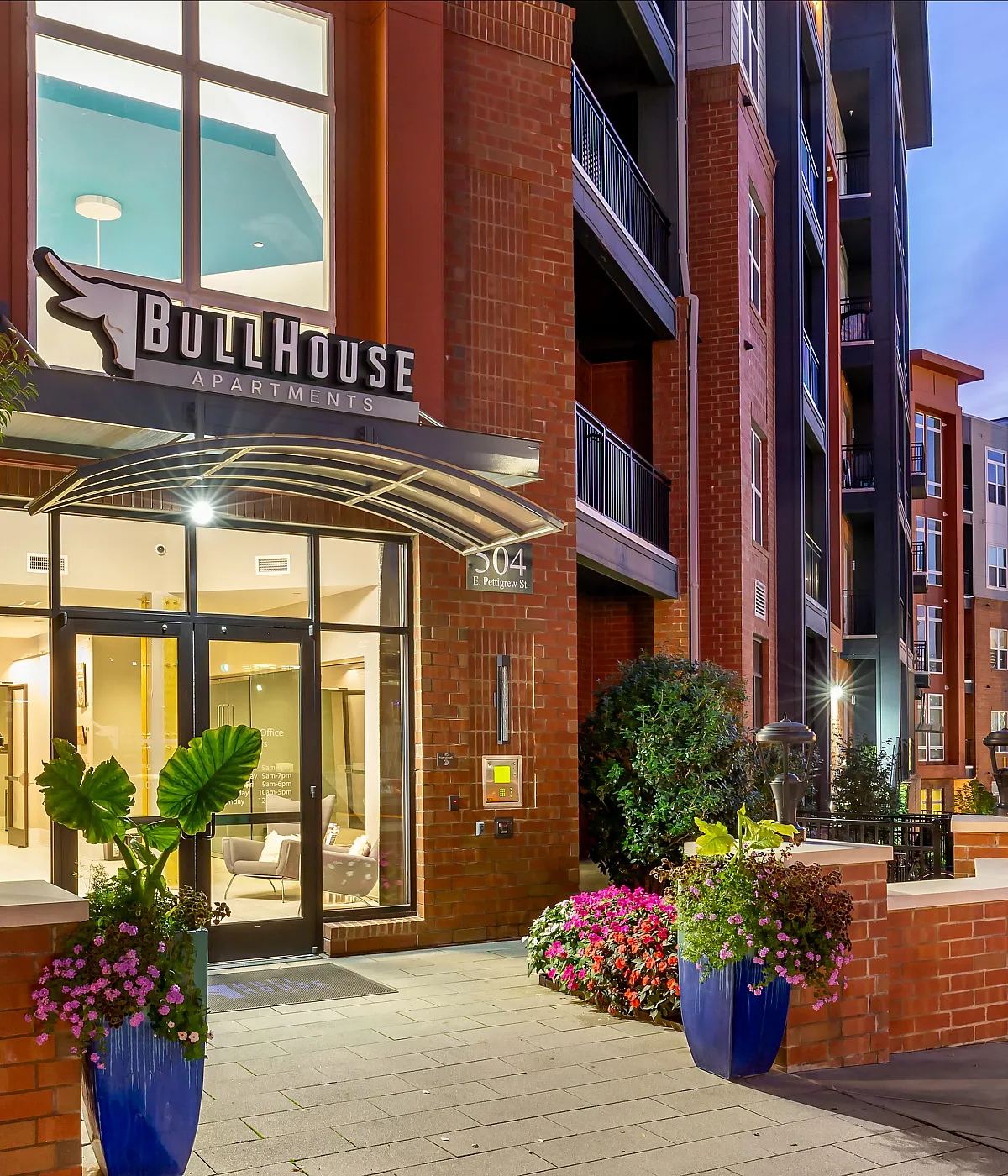 Elegant BullHouse Apartments entrance with modern design, vibrant flower arrangements, and welcoming atmosphere.