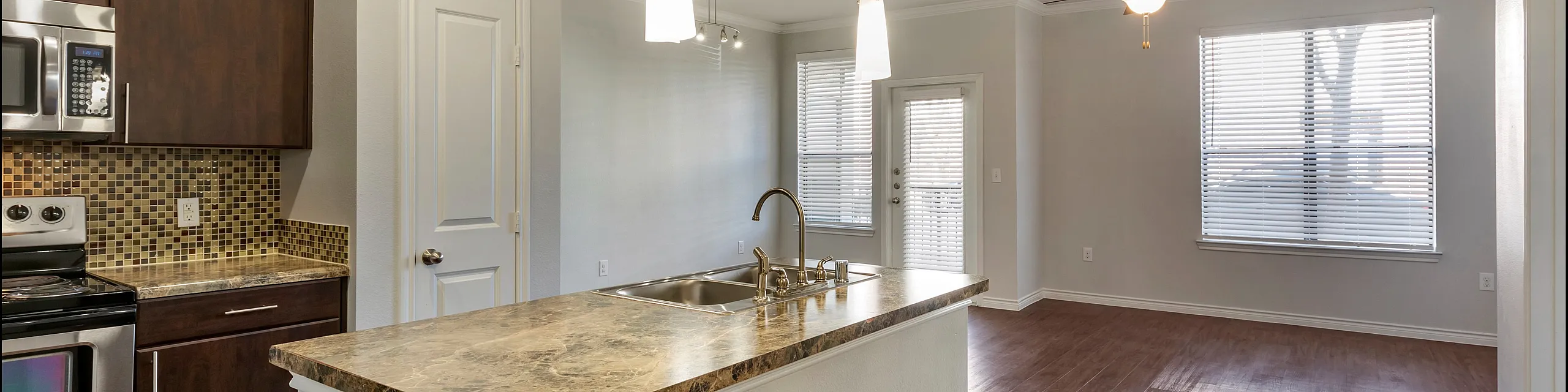 Bright open-concept kitchen and living area with modern fixtures, granite countertops, and sleek hardwood floors.