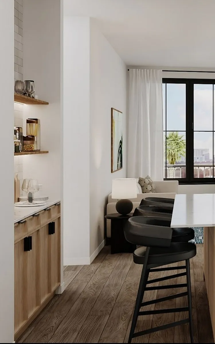 Modern kitchen and living area with sleek appliances, island seating, and a bright window view.