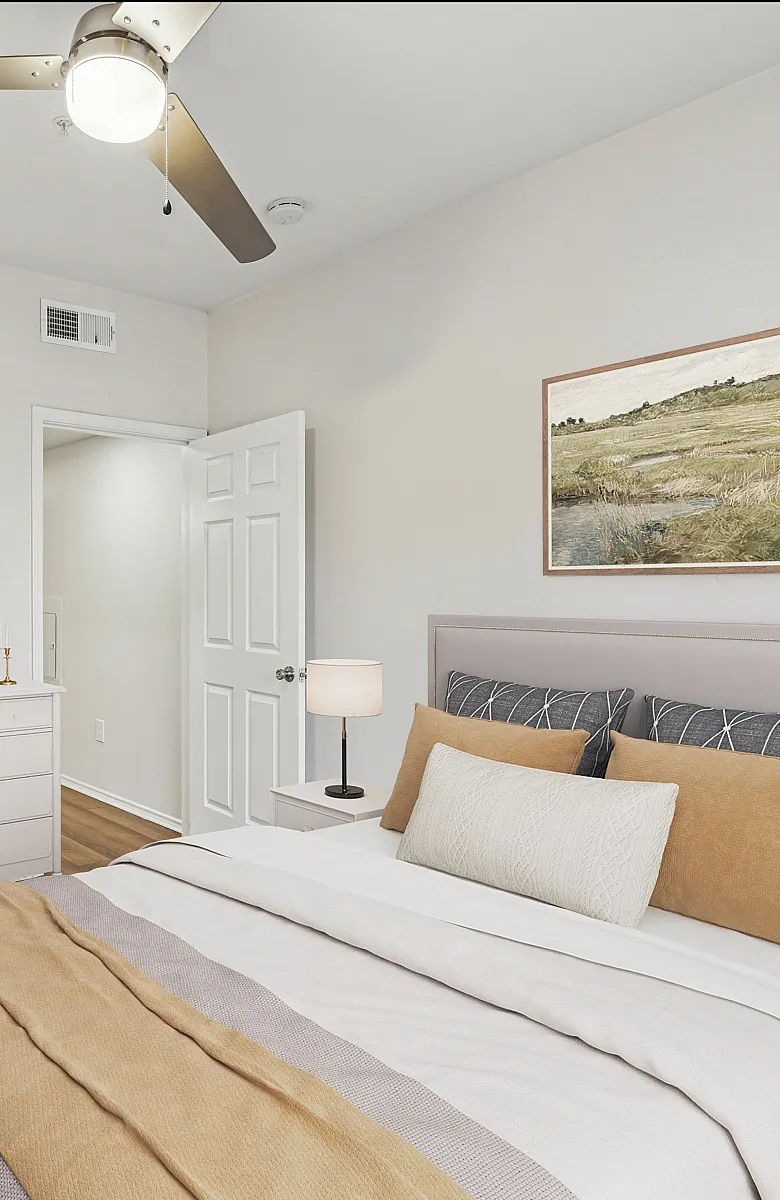 Charming bedroom with elegant decor, featuring a cozy bed with tasteful cushions, a stylish ceiling fan, and a scenic wall art.