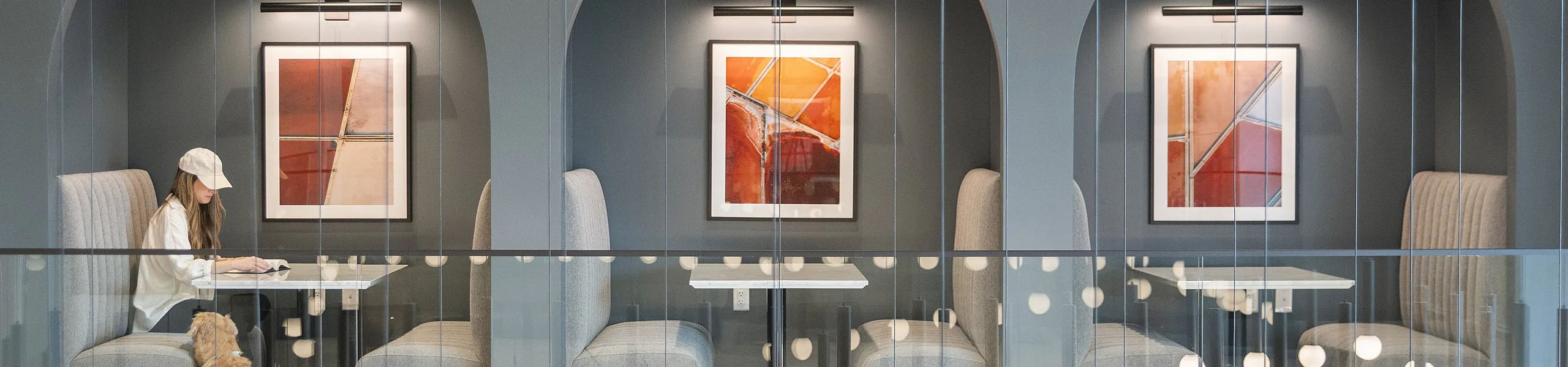 Modern seating area with elegant archways and abstract art, featuring cozy booths and stylish lighting, perfect for a relaxed meeting or quiet study.