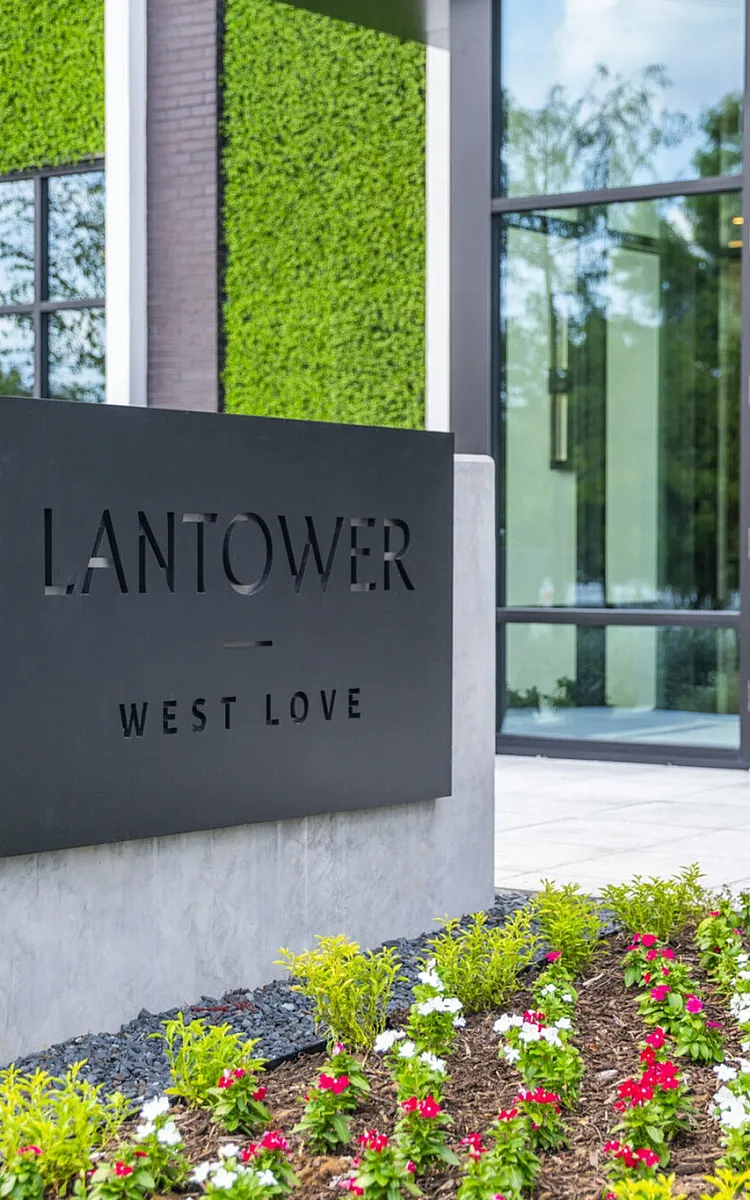 Chic entrance of Lantower West Love featuring modern architecture and lush landscaped gardens.