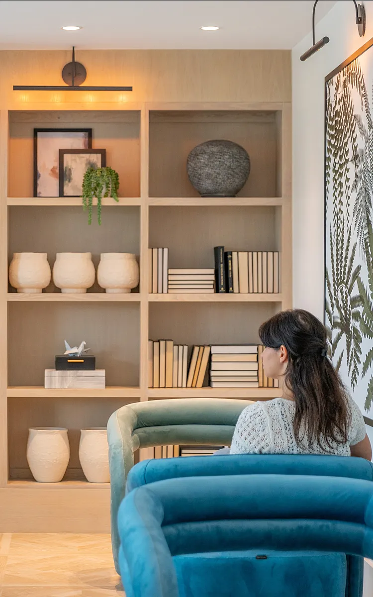 Chic home library with stylish bookshelves, decorative vases, and cozy blue chairs, creating a serene reading nook.
