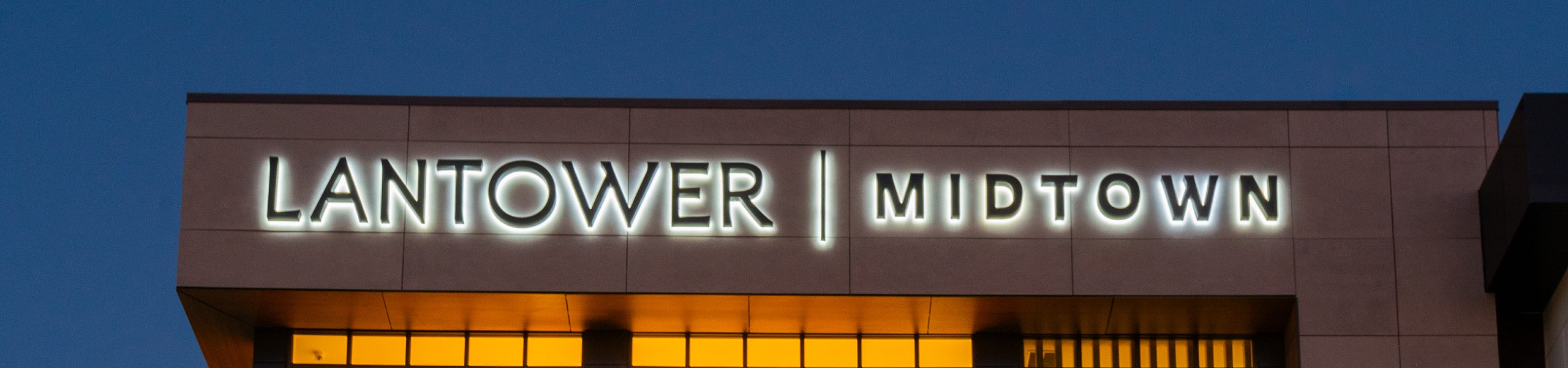 Modern Lantower Midtown building with large, illuminated glass windows and stylish facade, perfect for vibrant city living.