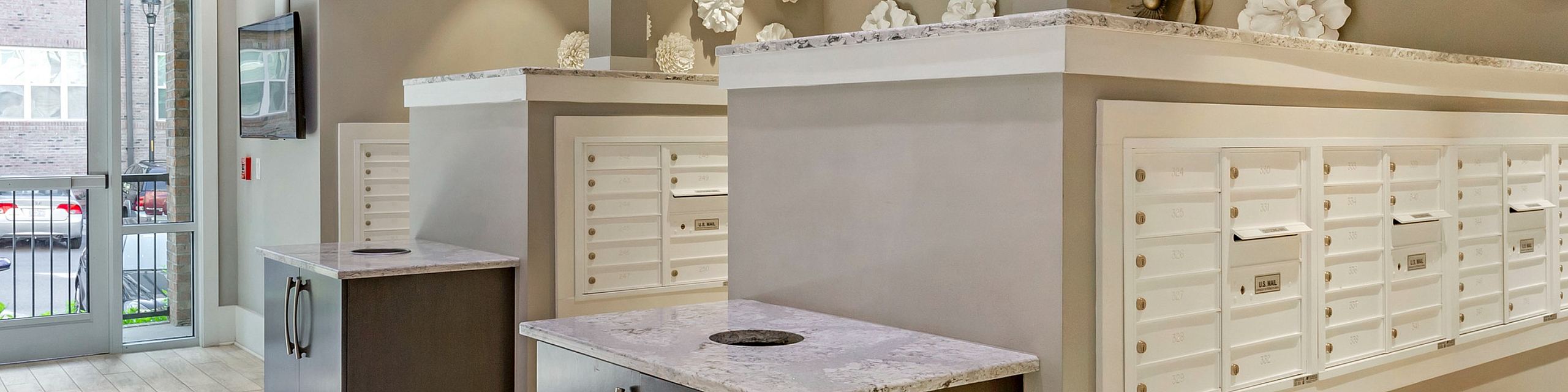 Elegant mailbox area with modern decor and stylish wall art in a well-lit apartment complex entryway.