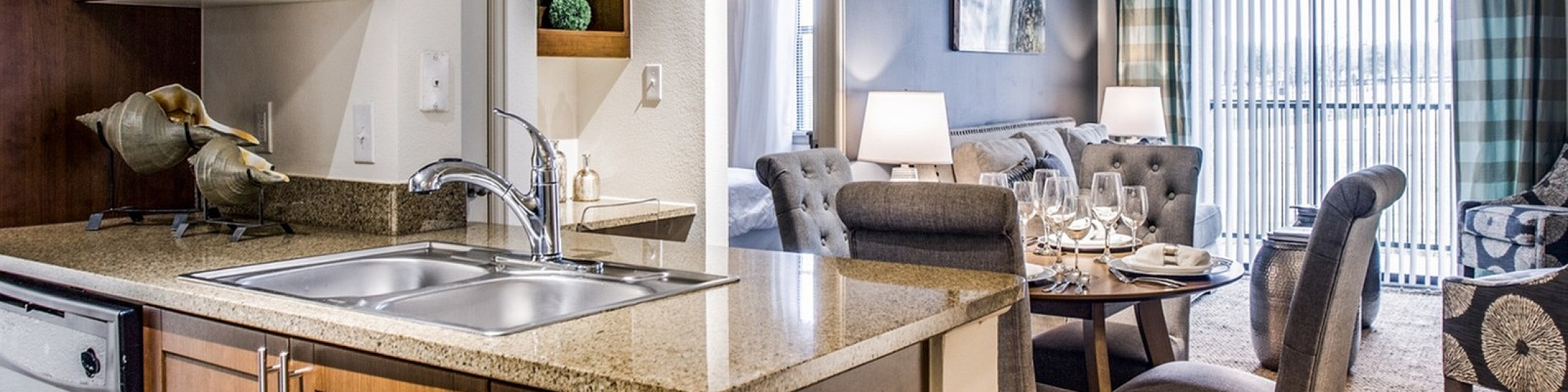 Modern open-concept living space featuring a sleek kitchen with granite countertops, cozy dining area, and stylish living room with large windows and elegant decor.