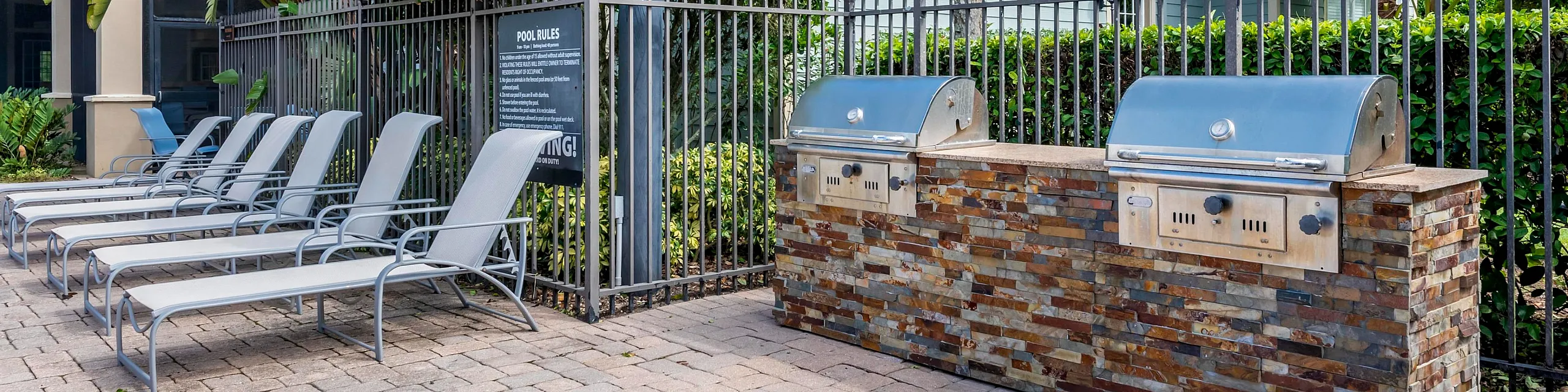 Charming outdoor area featuring a modern barbecue station and relaxing lounge chairs, surrounded by lush greenery.