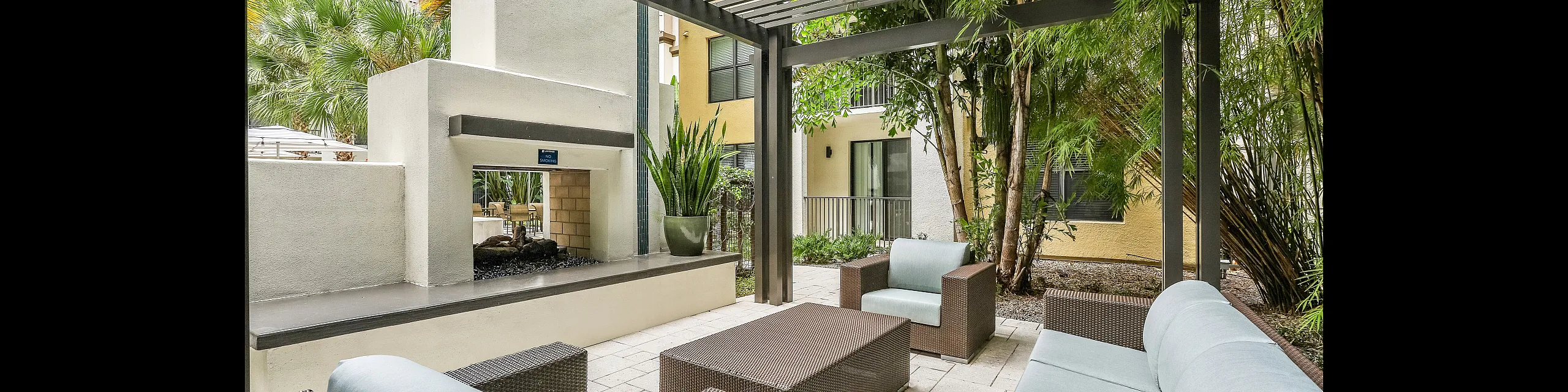Chic outdoor space featuring modern wicker seating and lush greenery under a stylish pergola.