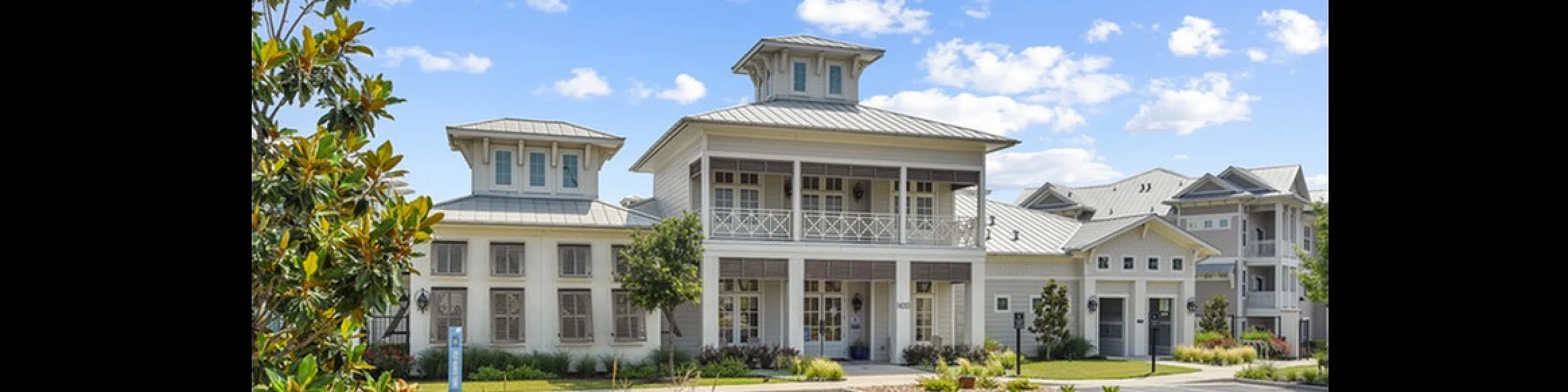 Charming residential complex with elegant architecture, vibrant landscaping, and a sunny exterior against blue skies.